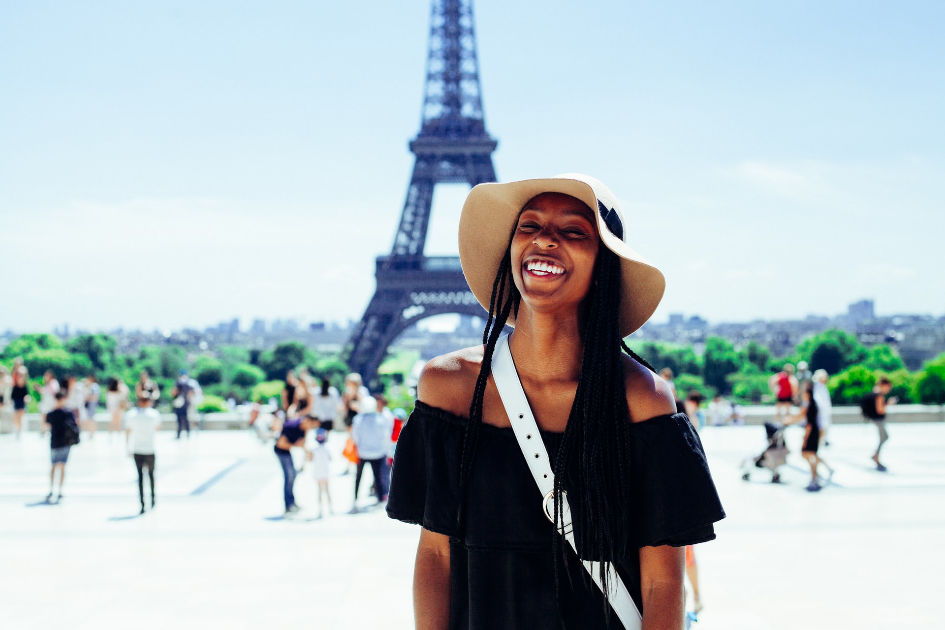 En glad student i Paris framför Eiffeltornet. Foto: Unsplash.